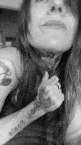 a black and white photo of a woman with tattoos on her arms .