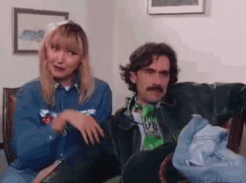 a man and a woman are sitting next to each other on a couch in a living room .