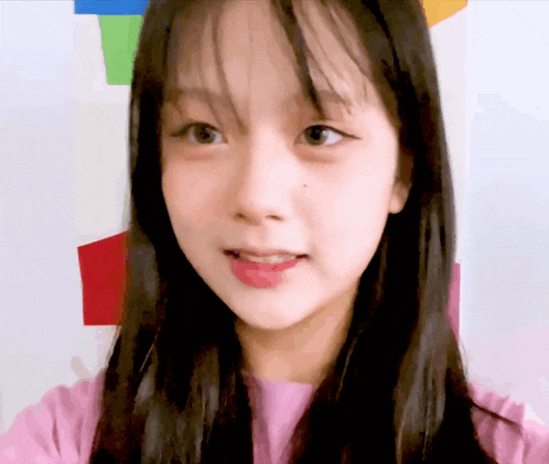 a close up of a young girl 's face with a pink shirt on