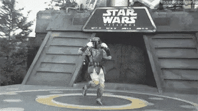 a man in a star wars costume is running in front of a star wars sign .