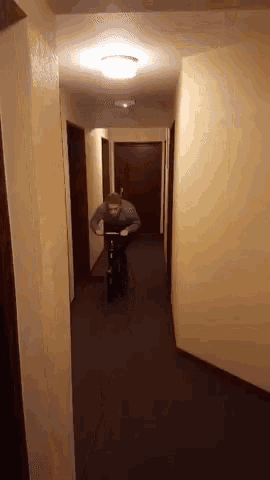 a man is riding a scooter down a hallway in a dark room