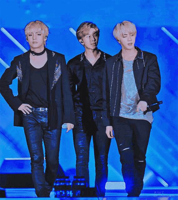 three men are standing next to each other on a stage