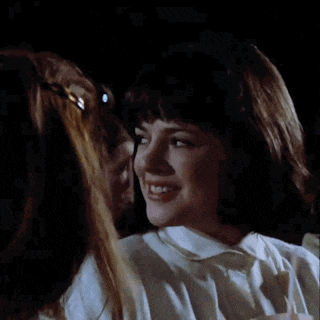 a woman in a white shirt smiles while looking at another woman