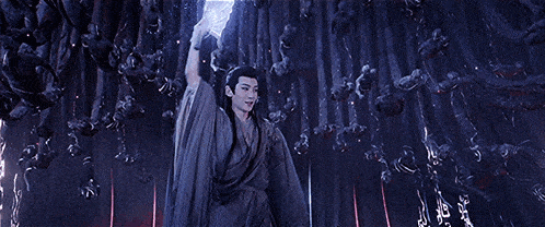 a man in a cape is flying through the air with a light coming out of his chest .
