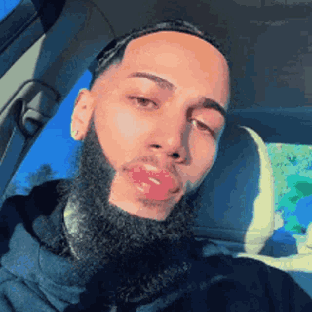 a man with a beard is sitting in a car and taking a picture of himself .