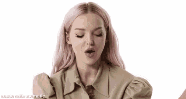 a woman with pink hair is wearing a khaki shirt and making a funny face .
