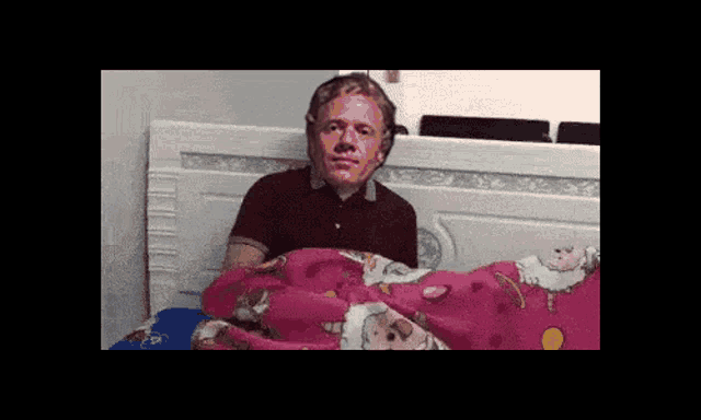 a man with pink paint on his face is laying in bed with a pink blanket