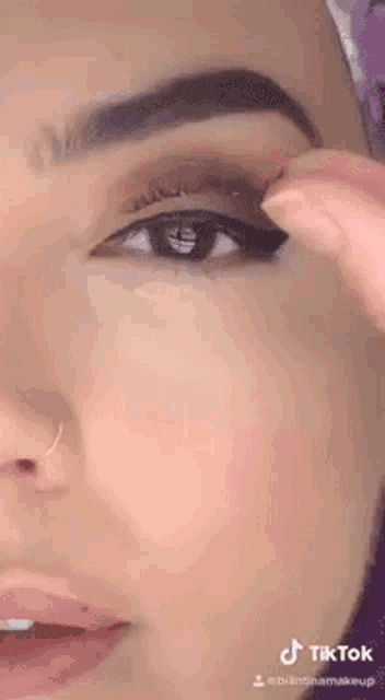 a close up of a woman applying makeup to her eye