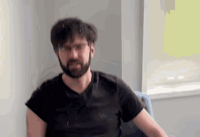 a man with a beard and glasses is sitting in a chair and looking at the camera .