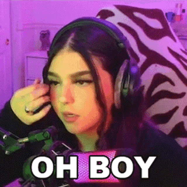 a woman wearing headphones is sitting in front of a microphone with the words oh boy written on it .
