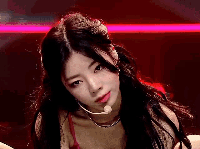 a woman with long black hair is wearing a red top and a necklace