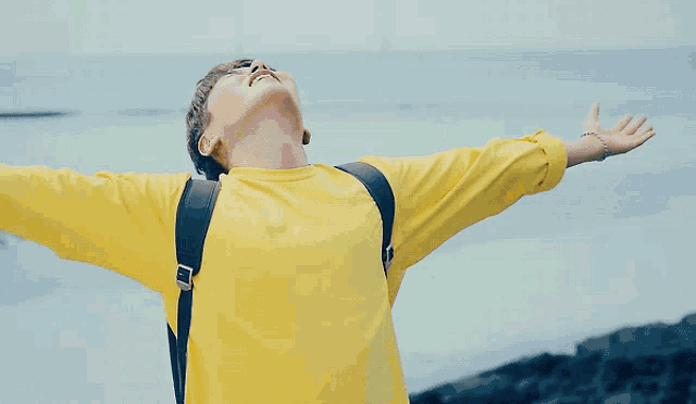 a person with their arms outstretched wearing a yellow shirt that says happy on it