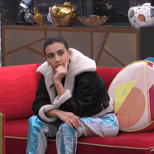 a woman sits on a red couch with a pillow that says ' i love you ' on it