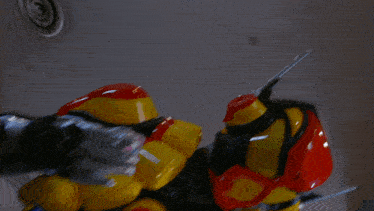 a yellow and red robot with a blue glove on