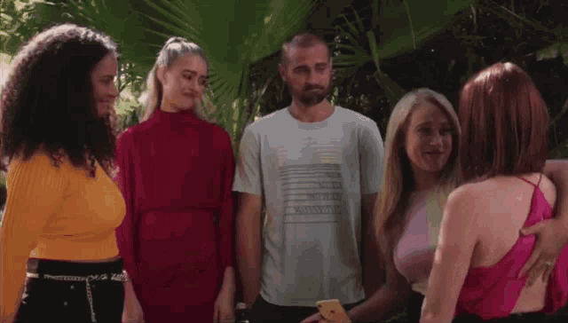 a man wearing a t-shirt that says ' emporio armani ' on it is surrounded by three women