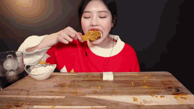 a woman in a red sweater is eating a piece of food