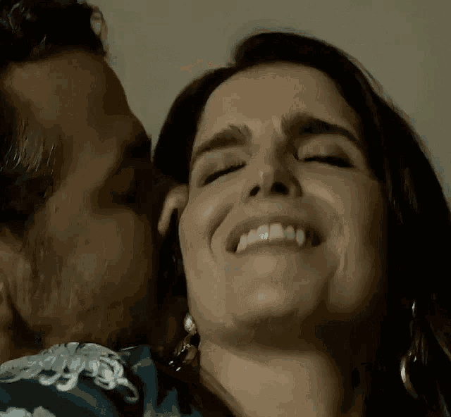 a man is kissing a woman on the cheek and she is smiling