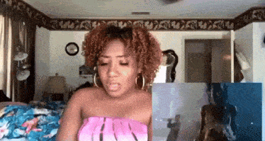 a woman in a pink top is standing in a bedroom looking at a picture of a dog .