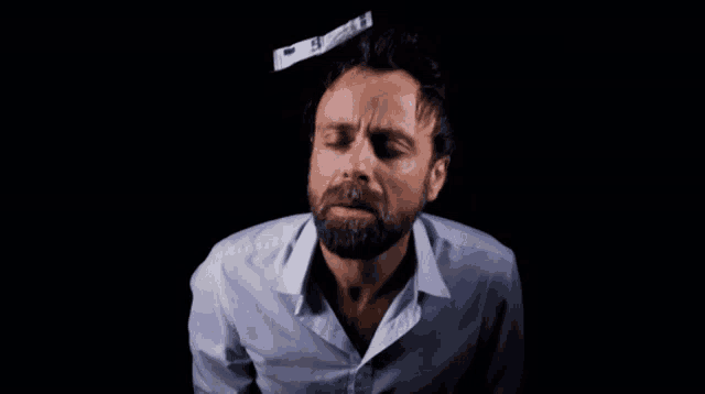 a man with a beard and a white shirt is blowing money into the air