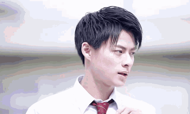 a young man in a white shirt and red tie looks to his left