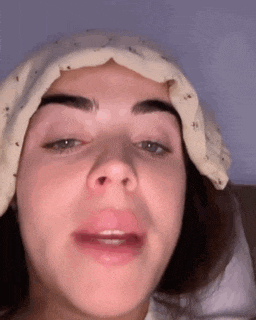 a close up of a woman 's face with a towel wrapped around her head .