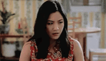a woman in a red dress is sitting at a table in a living room .