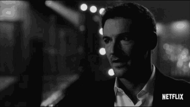 a black and white photo of a man in a suit and white shirt with netflix written on the bottom .