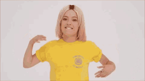a woman wearing a yellow t-shirt is smiling and hugging .