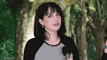 a woman is holding a microphone in her hand while standing in front of trees .