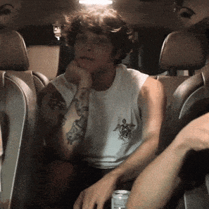 a man with a tattoo on his arm is sitting in the back of a car