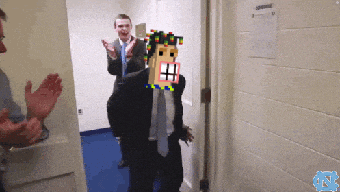 a man in a suit and tie stands in a hallway with a schedule on the wall behind him