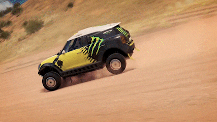 a yellow and black monster energy car is driving on a dirt road