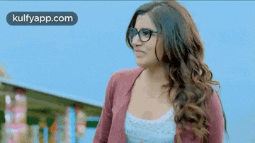 a woman wearing glasses is making a funny face while standing in front of a building .