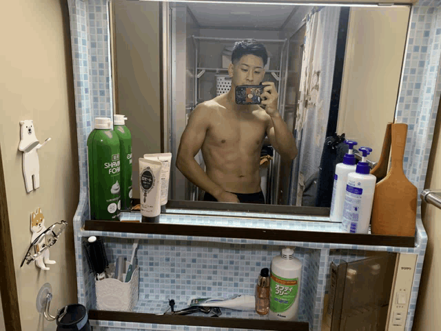 a man taking a picture of himself in a bathroom mirror with a bottle of shaving foam in the background