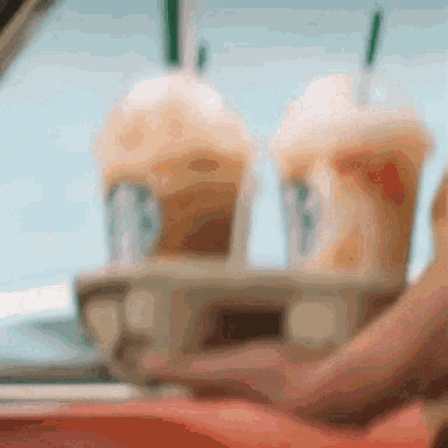 a blurred image of a person holding a tray of coffee cups