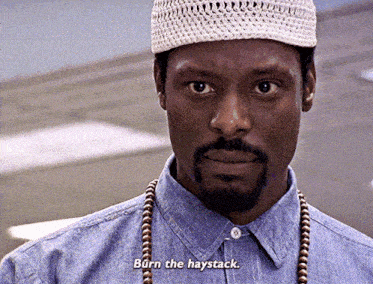 a man with a beard wearing a hat and a necklace says burn the haystack