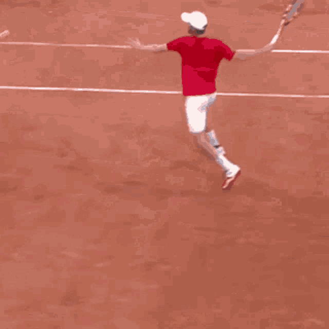 a man in a red shirt is running on a tennis court holding a tennis racket