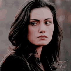 a close up of a woman 's face with long dark hair looking at the camera .
