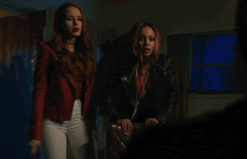 a couple of women standing next to each other in a dark room