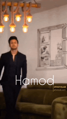 a man in a suit is standing in front of a couch with the word hamo on the bottom