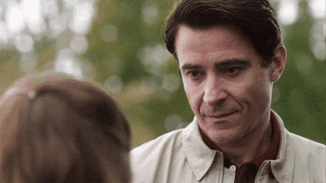 a man in a white jacket is looking at a girl in a red shirt