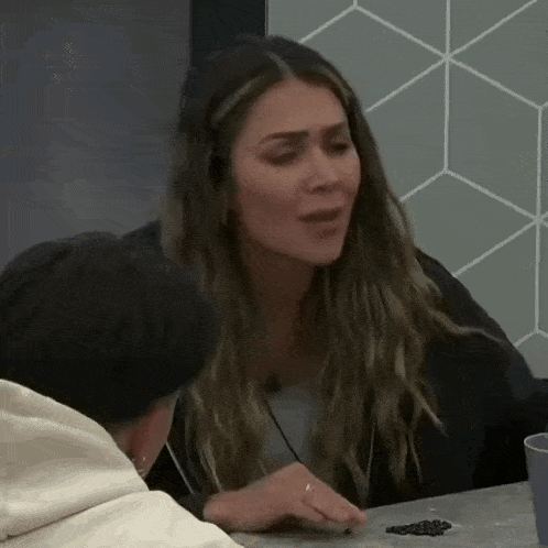 a woman is sitting at a table with a man and talking .