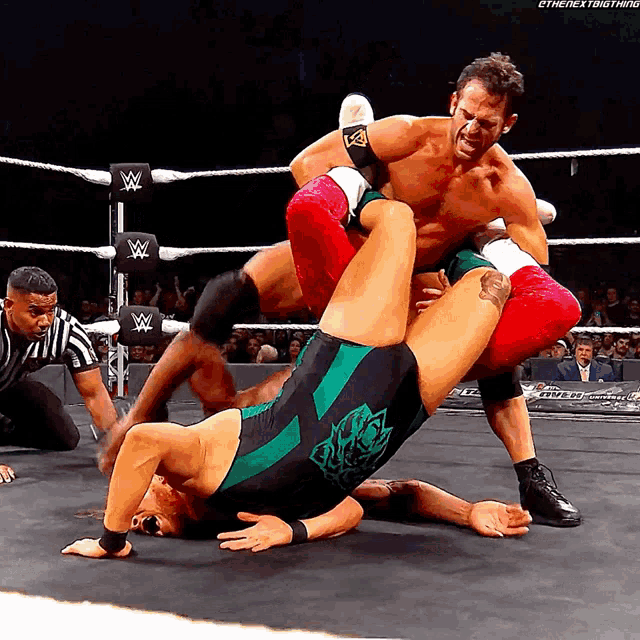 a man in a green and black wrestling outfit is wrestling another man