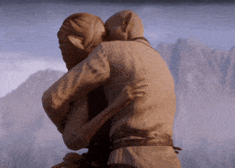 a man and a woman are hugging each other in front of mountains