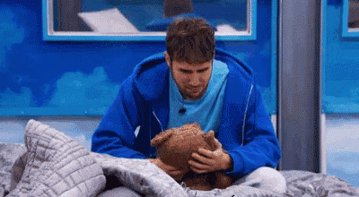 a man in a blue hoodie is holding a teddy bear in his lap .