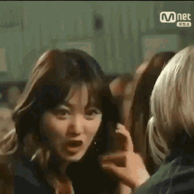 a woman is talking on a cell phone while another woman holds her hair .