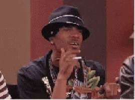 a man wearing a hat and a necklace is smoking a cigarette