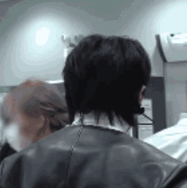 a man wearing a headset and a leather jacket is talking on a cell phone .