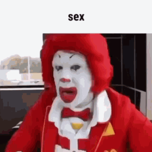 a mcdonald 's clown is wearing a red hat and a bow tie and looking at the camera .