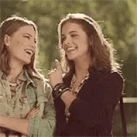 two women are standing next to each other laughing and smiling